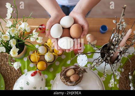 Eggs in the hands of a child on the background of Easter decorations. Stock Photo