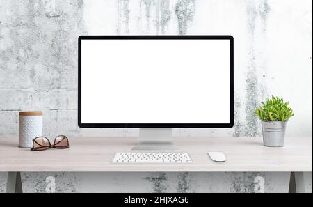 Computer display on office desk with isolated screen for mockup, wep page presentation. Clean desk with plant, glasses and box. White rough wall in th Stock Photo