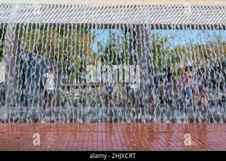 Tourists behind the waterfall of the Water Gardens in the Parque das Nacoes / EXPO 98 in Lisbon, Portugal Stock Photo