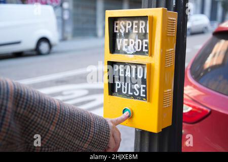 senior Caucasian woman's hand pressing the yellow traffic light button with green button Stock Photo