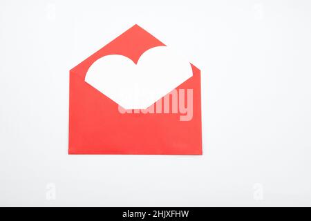Open red envelope made of origami paper from white a white heart flies out, isolated on a white background. Stock Photo