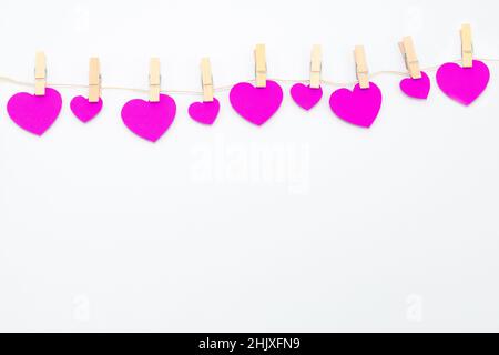 Pink hearts with clothespins hanging on clothesline isolated on white background. Stock Photo