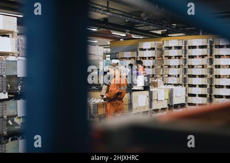 Male and female blue-collar workers working in warehouse of factory Stock Photo