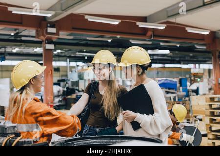 Smiling businesswomen discussing with female worker in factory Stock Photo
