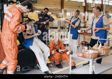 Happy male and female workers having snacks in warehouse Stock Photo