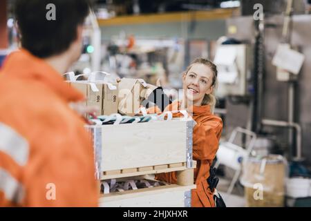 Smiling female worker talking with male coworker while working in warehouse Stock Photo