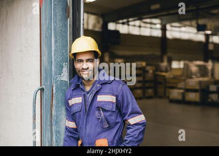 Portrait of smiling blue-collar worker wearing hardhat in warehouse Stock Photo