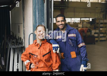 Confident male and female blue-collar workers in protective workwear at factory Stock Photo