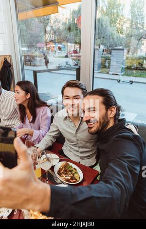 Smiling man taking selfie with male friend in bar Stock Photo