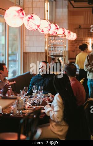 Male and female friends talking while having wine in bar during party Stock Photo