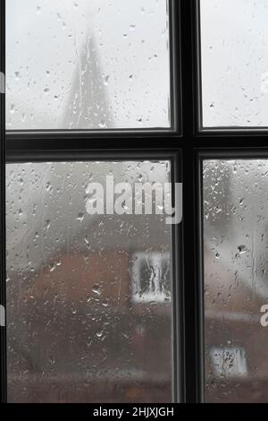 Rain on glass window pane with church spire in background, Burwash, East Sussex, England, United Kingdom, Europe Stock Photo