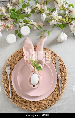 Easter dinner with white bunny, fresh spring flowers and eggs. Elegance pastel and pink tablescapes. View from above. Christian religion tradition. Ve Stock Photo