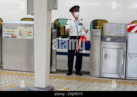 TOKYO, JAPAN - September 29, 2021: A station worker with a flag on a platform at Tokyo Station by a bullet train. Stock Photo