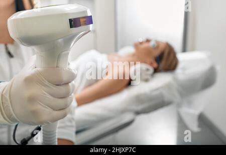 Beautician holding Lumecca device with intense pulsed light IPL technology for photorejuvenation of a woman's body and removal of brown spots and frec Stock Photo