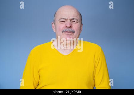 Hispanic old man suffering from pain, isolated on blue wall Stock Photo