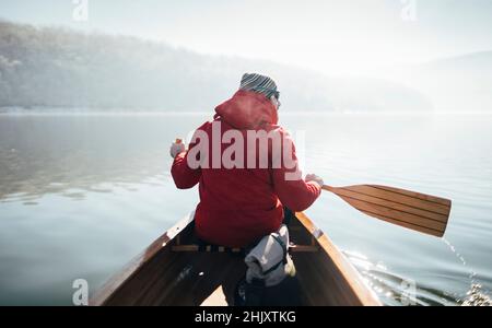 Rear view of man paddling canoe on the winter sunny day Stock Photo