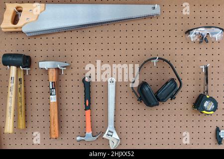 Picture hanging on the wall with various types of tools, including saws, goggles, tape measure and hammers. Stock Photo