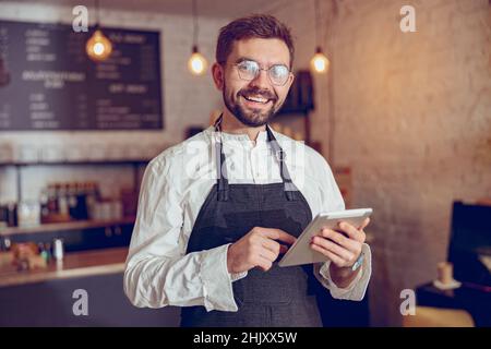 Joyful male worker using tablet computer in cafe Stock Photo