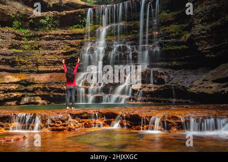 young girl standing near waterfall flowing streams falling from mountain at morning from low angle image is taken at wei sawdong falls cherrapunji soh Stock Photo