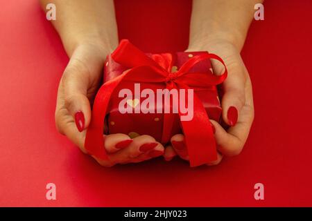 valentine. gift in hands on a red background. selective focus Stock Photo
