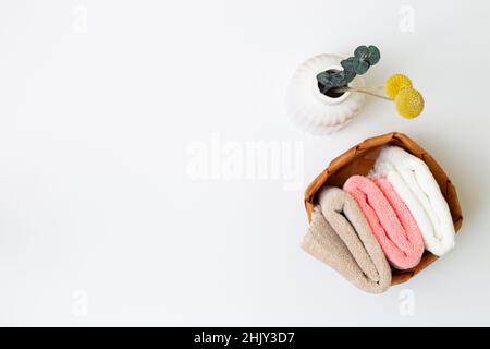 Bath towels in basket and vase of dry flowers on white background. top view, copy space Stock Photo