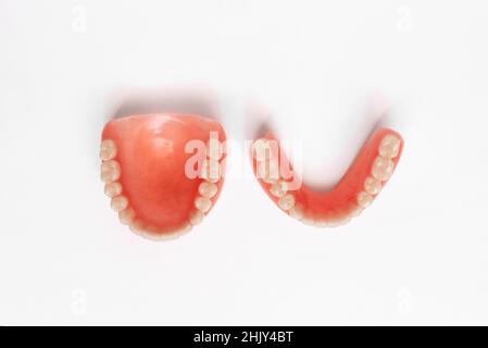 Top view of complete denture on white background. Full denture close-up. Dentures. Isolate on white background. Full removable plastic denture of the Stock Photo