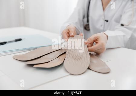 Doctor holding an insole while sitting at a table. Orthopedist tests the medical device. Orthopedic insoles. Foot care. Flat Feet Correction Stock Photo