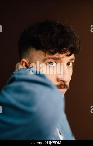 Portrait of man with hand behind head in studio Stock Photo