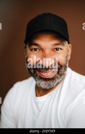 Smiling man with cap against brown background Stock Photo