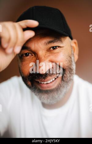 Happy mature man holding cap against brown background Stock Photo