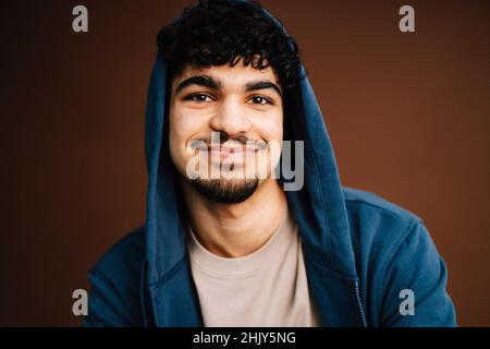 Portrait of smiling man wearing jacket against brown background Stock Photo