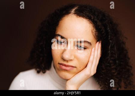 Contemplative woman over brown background Stock Photo