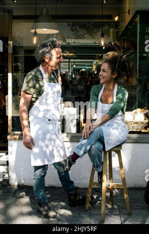 Smiling mature male and female colleagues talking by bakery Stock Photo