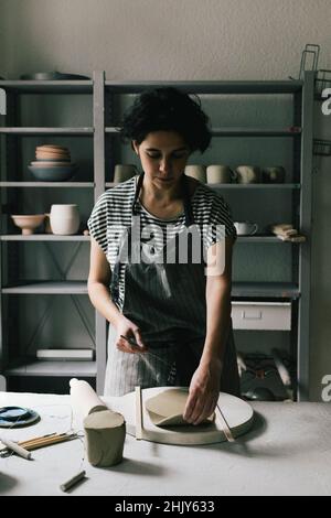 Female owner modeling clay at ceramics workshop Stock Photo