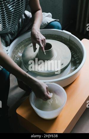 Mature female owner modeling shape to pot in ceramics store Stock Photo