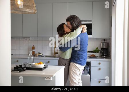 Affectionate mature couple kissing on mouth at home Stock Photo