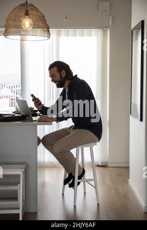 Mature businessman using smart phone while working at home Stock Photo