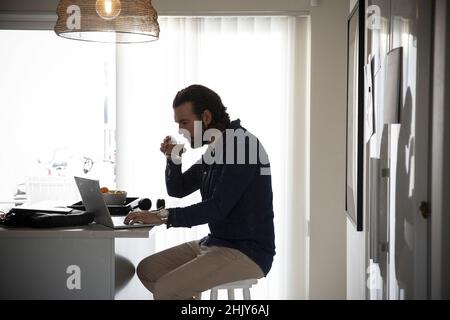 Male freelancer drinking coffee while working at home Stock Photo
