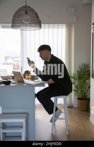 Male freelancer using smart phone while working from home Stock Photo