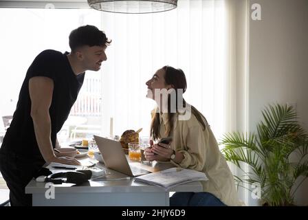 Smiling couple looking at each other while working together in kitchen Stock Photo