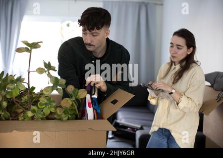 Young couple looking at box while relocating in new home Stock Photo