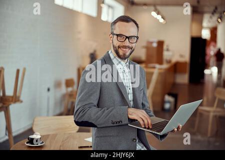 Joyful young man using notebook in cafe Stock Photo