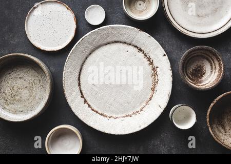Modern Trendy Craft Ceramic Plates And Bowls On Concrete Table Background. Top View Copy Space. Kitchenware Stock Photo