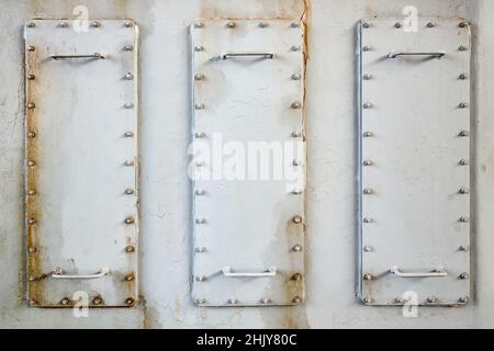 Three metal hatches plates on compressor for revision close-up with oil stains painted with gray paint bolted with studs and nuts background with Stock Photo