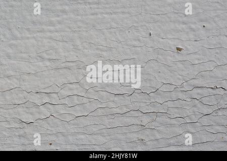 cracked surface of white painted metal. it can be used as background. Close-up texture of peeling and cracked white paint on wall surface. Stock Photo