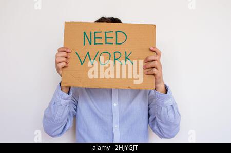 Unemployed man holding sign board with inscription NEED WORK. Concept of losing job and looking a new one. He is having financial problems. Stock Photo