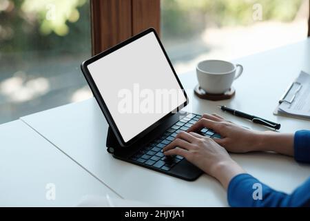 Mockup image of a woman using and touching on laptop touchpad with blank white desktop screen on wooden table Stock Photo