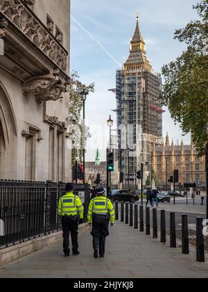 Uniformed London Metropolitan police officers walking into Parliament Square, Westminster, with Big Ben under renovation visible in the background. Stock Photo