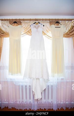 bride and bridesmaids dresses hanging on hangers Stock Photo - Alamy