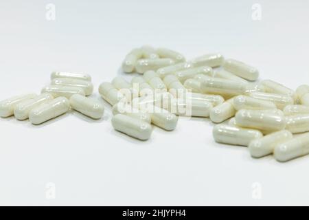 Close up of a pile of white capsules pills. Medications on white background Stock Photo